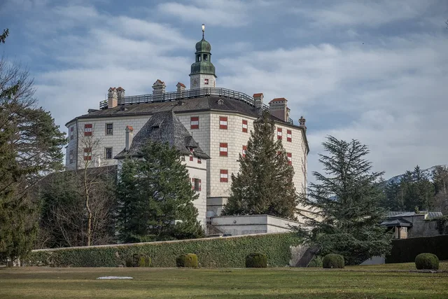 Historisches Schloss mit Turm, Garten und Bergen im Hintergrund