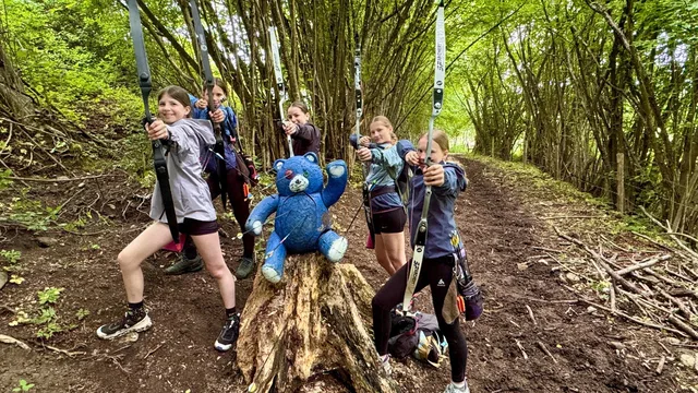 Gruppe mit Bögen und blauem Bärenziel im Wald