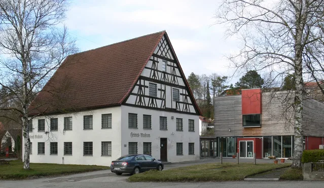 Historisches weißes Fachwerkhaus mit rotem Giebeldach neben modernem Holz-Glas-Anbau