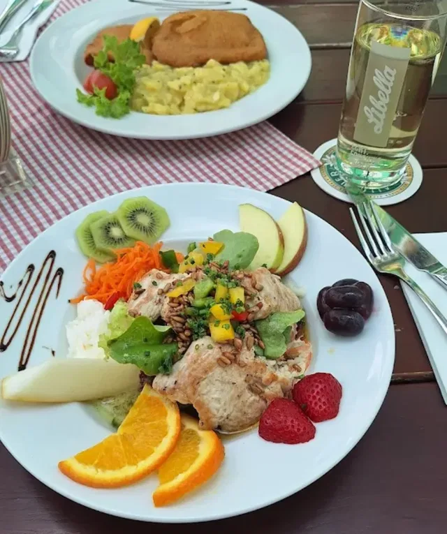 Zwei Gerichte am Tisch mit Salat und Obstgarnitur