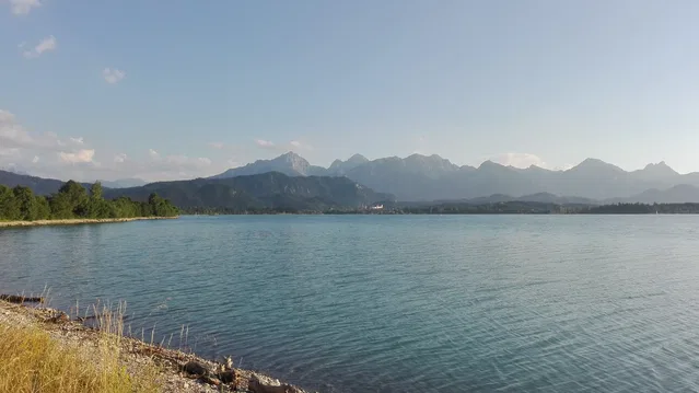 Blick über den Forggensee mit Bergkette im Hintergrund.