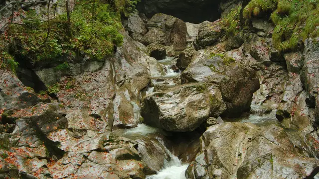 Wasserlauf zwischen Felsblöcken und herbstlichem Wald in der Starzlachklamm. Ortsmotiv.