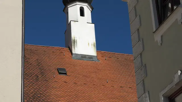 Historisches Colleggebäude in Mindelheim mit Ziegeldächern und kleinem Turm vor blauem Himmel. Ortsmotiv zur Ausflugsplanung.