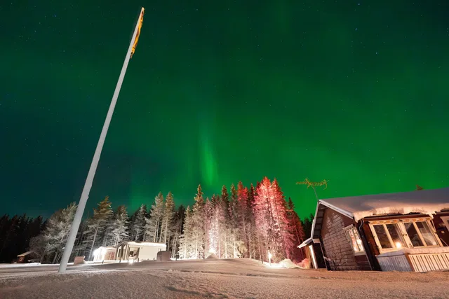 Nordlichter über der verschneiten Unterkunft von Lappland Tour
