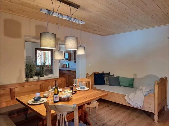 Gedeckter Holztisch in einer hellen Wohnküche mit Sitzbank und Pendelleuchten.