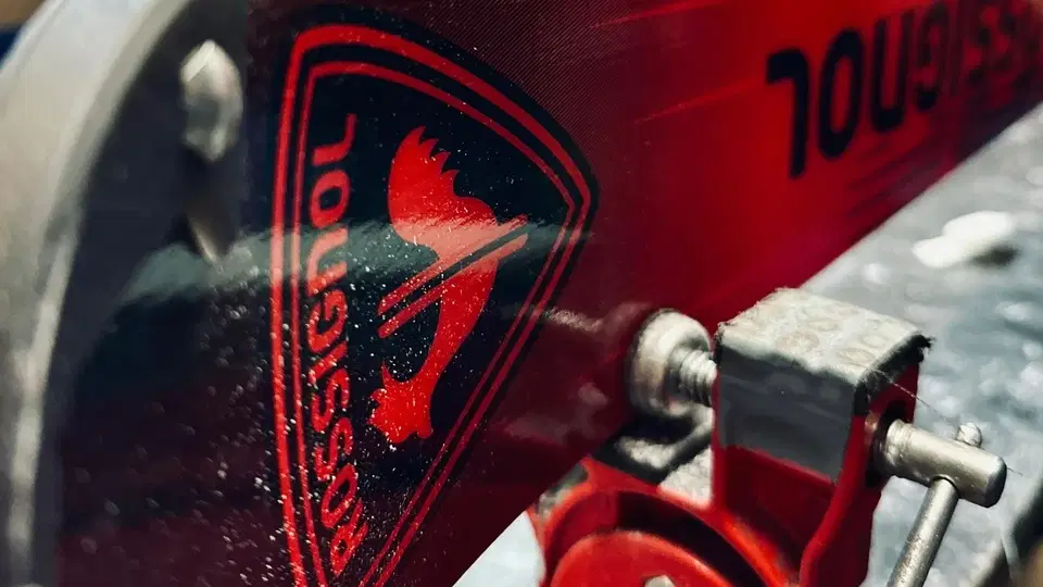 Roter Ski mit Bindung und Logo in Nahaufnahme.