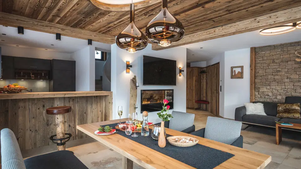 Wohn- und Essbereich mit Holztisch, offener Küche und Effektkamin