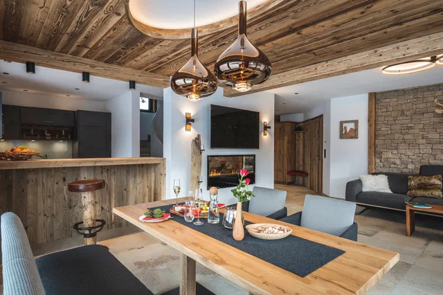 Wohn- und Essbereich mit Holztisch, offener Küche und Effektkamin