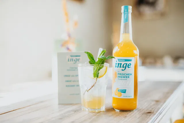 Ingwergetränk mit Minze neben einer Flasche Inge im bene.