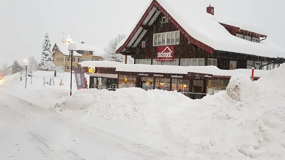 Verschneites Chalet mit Ladenfront in einer Berglandschaft.