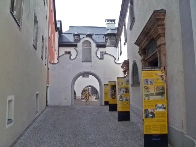 Historischer Klosterinnenhof mit Torbogen, Statue und Informationstafeln