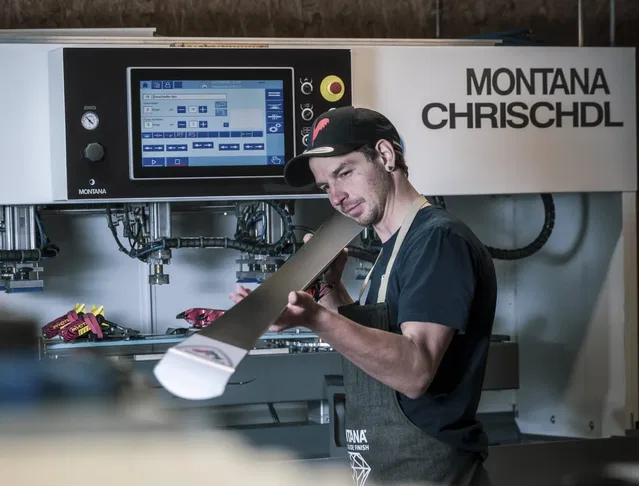 Mann in schwarzer T‑Shirt und Schürze arbeitet an einer großen Montana‑Maschine mit Touchscreen-UI.