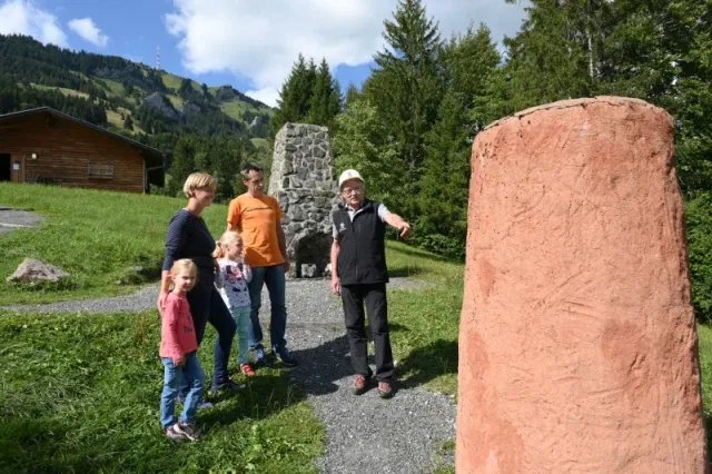 Familie mit Guide neben einem historischen Hochofenmodell