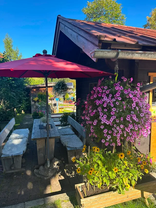 Außenterrasse am Minigolfplatz Baad mit Sitzbänken und Blumen
