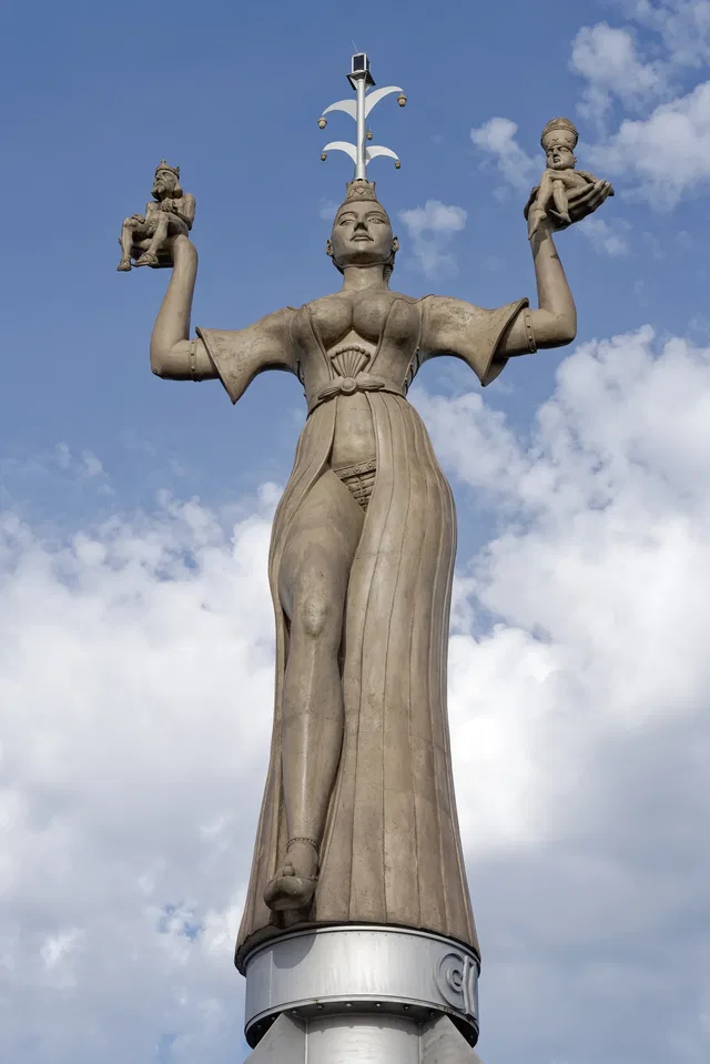 Imperia-Statue am Konstanzer Hafen mit zwei kleinen Figuren auf ihren erhobenen Händen.