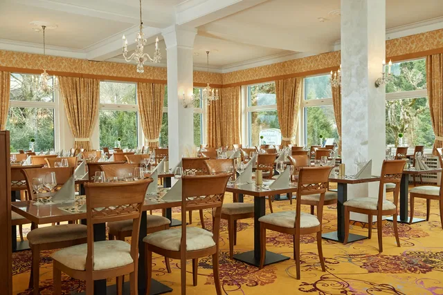 Speisesaal des Restaurants im Wittelsbacher Hof mit gedeckten Tischen und Kronleuchtern