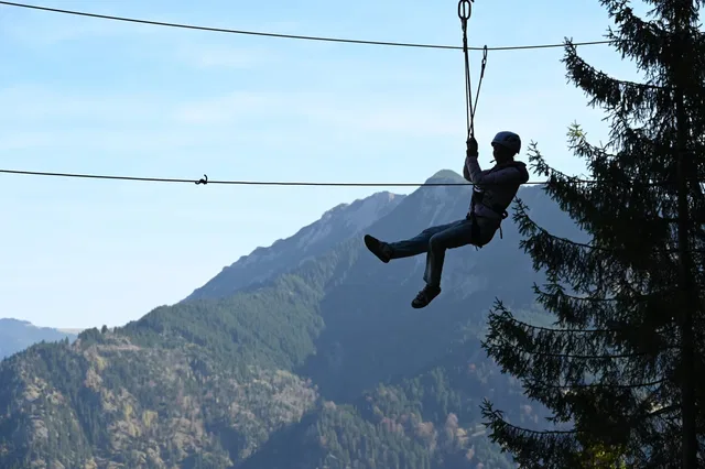 Person auf einer Seilrutsche vor einer Berglandschaft