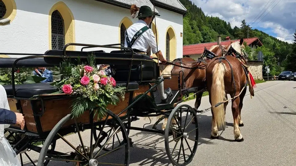 Blumengeschmückte Kutsche mit Pferdegespann vor einer Kirche