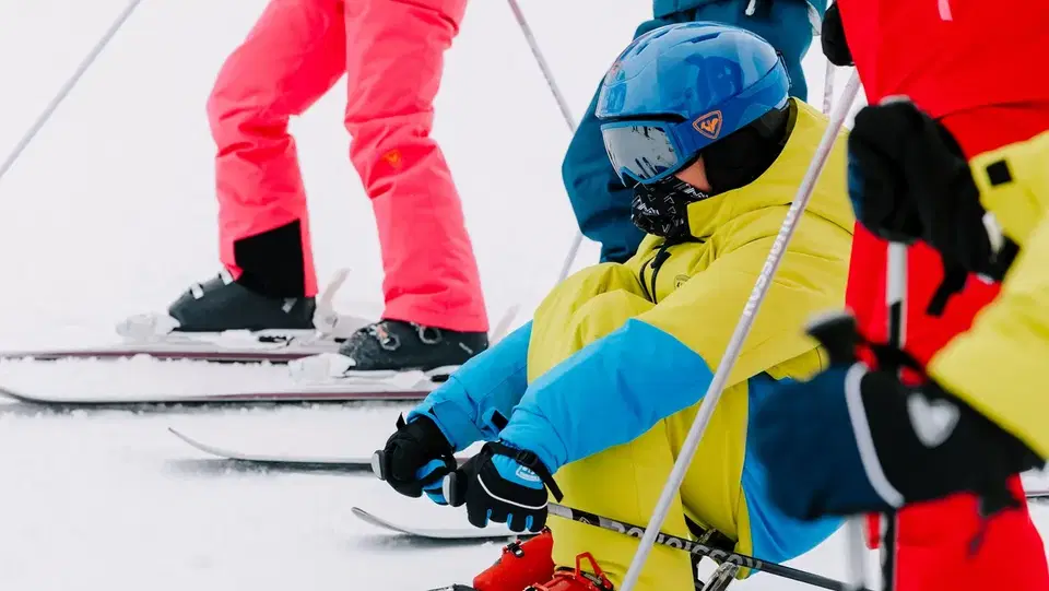 Gruppe Skifahrerinnen und Skifahrer in bunten Anzügen auf Skiern im Schnee