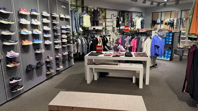 Laufschuhe und Sportbekleidung im Laden mit Anprobebank