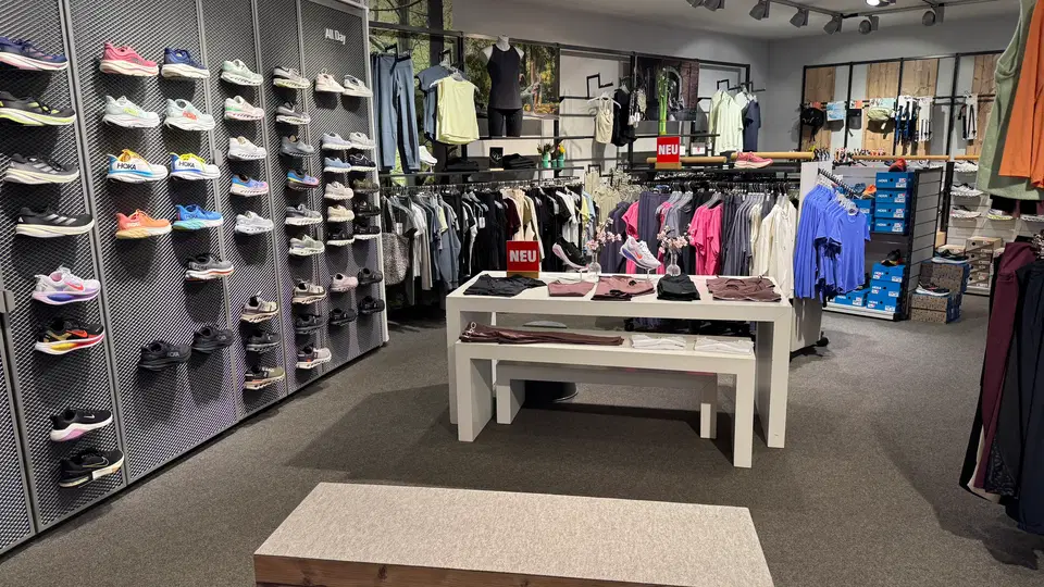 Laufschuhe und Sportbekleidung im Laden mit Anprobebank