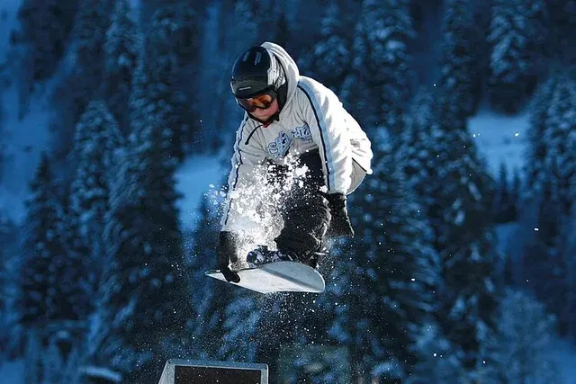 Snowboarder in Winterlandschaft beim Sprung über ein Hindernis.