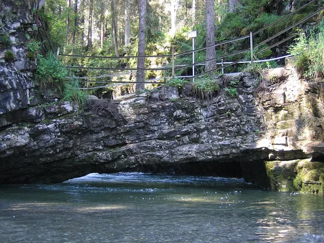 Felsbogenbrücke aus Stein über einem Fluss im Wald