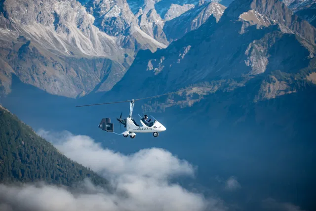 Tragschrauber im Flug vor einer Bergkulisse