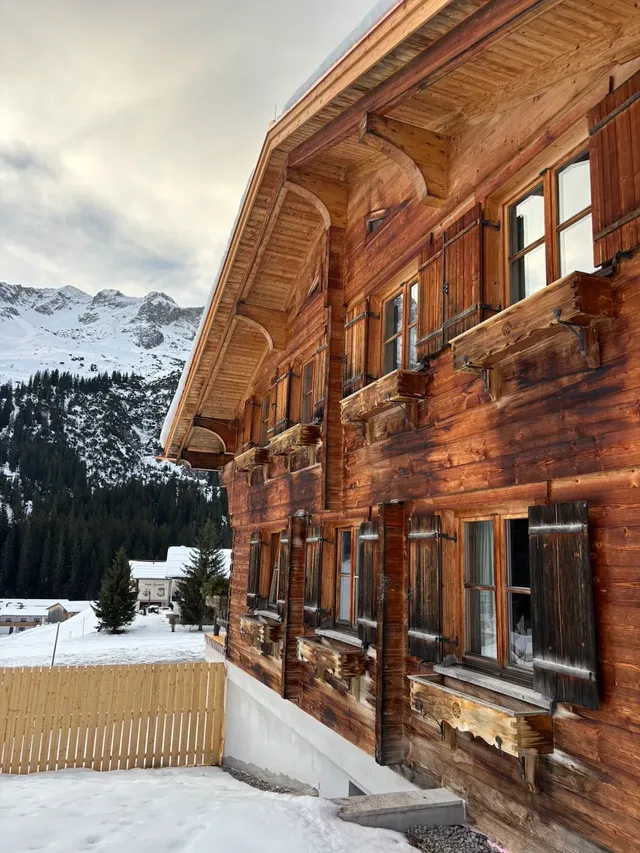 Holzhaus im Schnee mit Balken und verschneiter Umgebung
