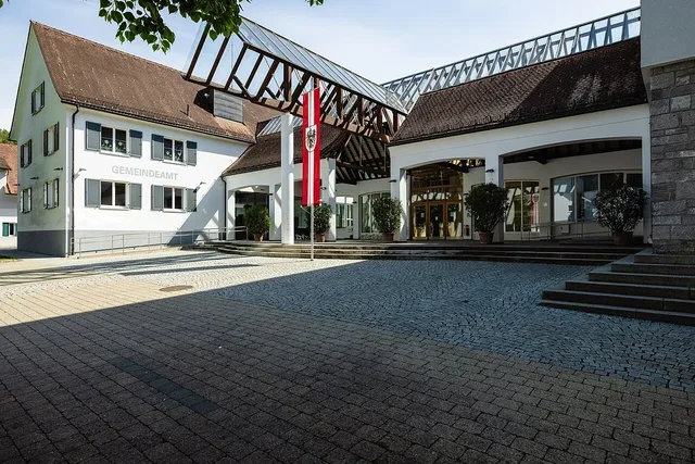 Gebäudekomplex eines Gemeindeamts mit Eingang, Flagge und Treppe