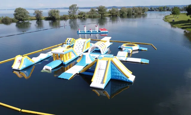 Schwimmender Wasserpark mit bunten Rutschen auf einem ruhigen See.