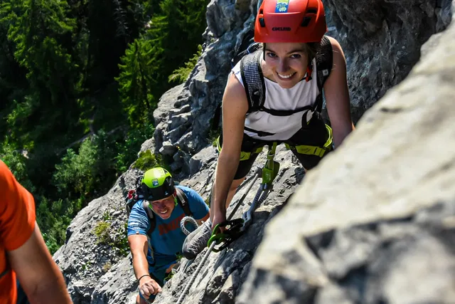 Teilnehmende mit Helm und Klettersteigset am Fels