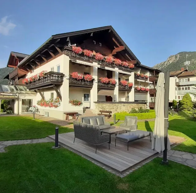 Hotel Garni Schellenberg im Alpenstil mit Blumenkästen auf Balkonen und Gartenlounge.