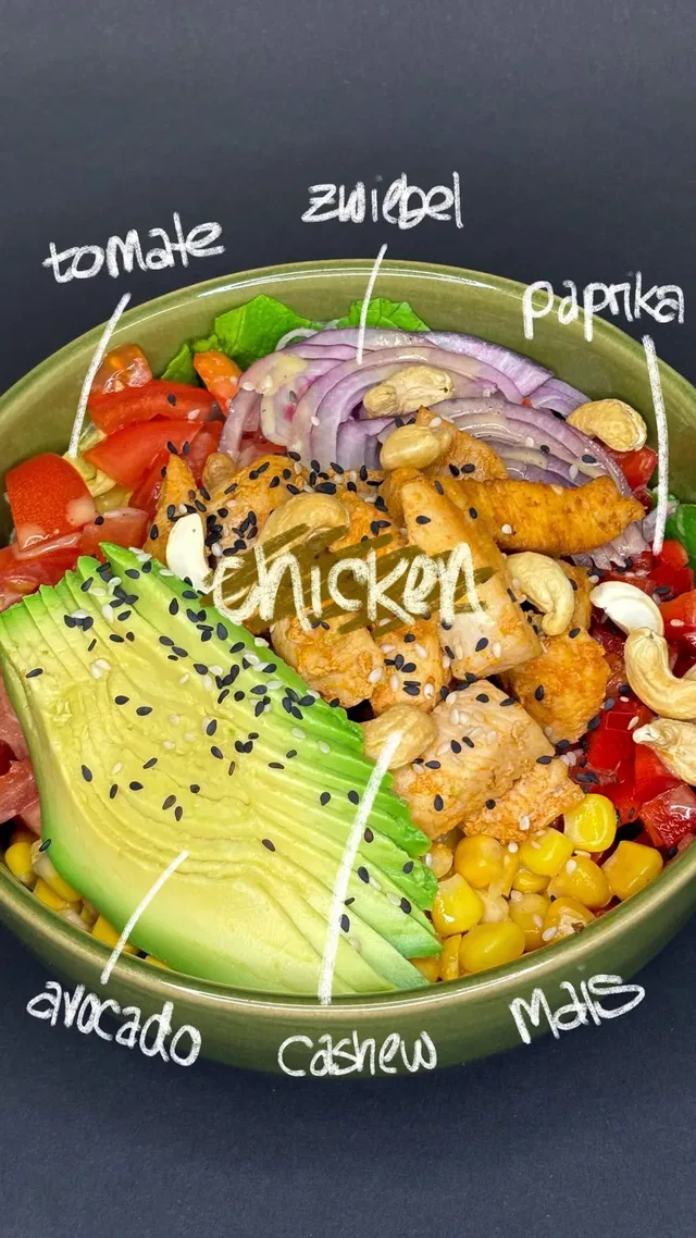 Bunte Bowl mit Avocado, Hähnchen, Mais, Tomate, Paprika, Zwiebel, Cashews und Sesamsamen.