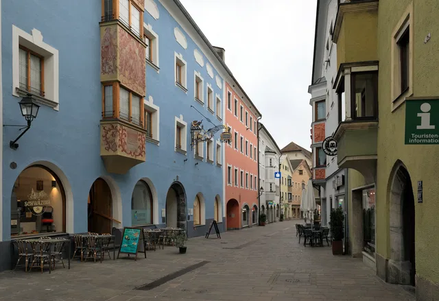 Farbenfrohe Altstadtgasse mit Cafés und Schild zur Touristeninformation