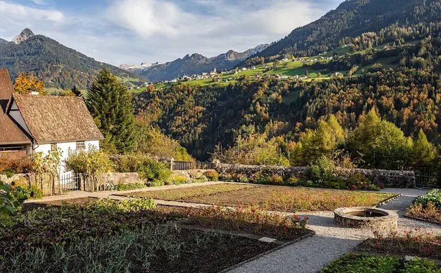 Garten der Propstei als Motiv am Ausgangsort; der Themenweg verläuft im Wald unterhalb der Anlage.