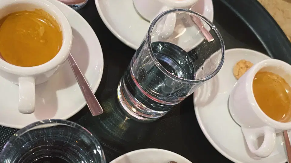 Kaffeetassen mit Wassergläsern und Gebäck auf einem Tablett