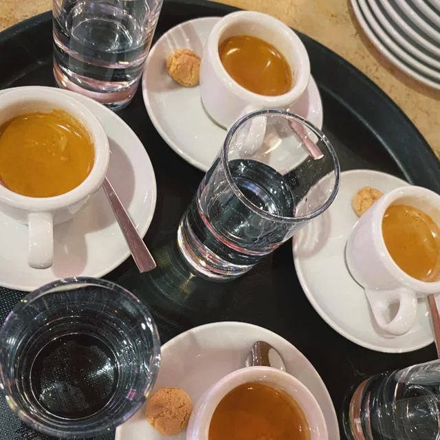 Kaffeetassen mit Wassergläsern und Gebäck auf einem Tablett
