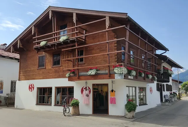Mehrstöckiges Chalet-Gebäude mit Holzfassade, weißem Ladenbereich und Blumenkästen