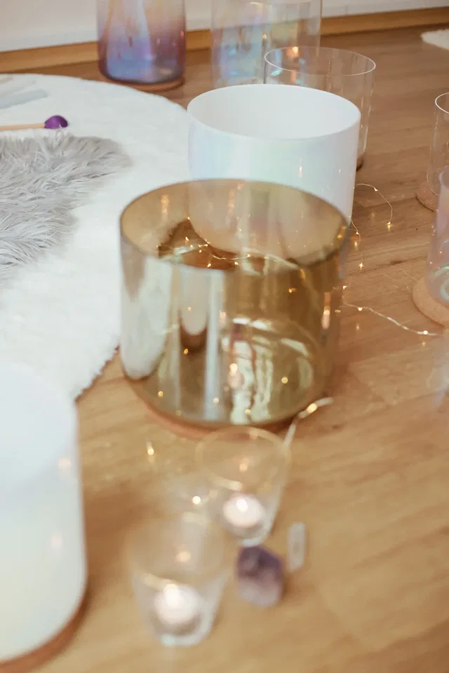 Goldener Kerzenhalter und Gläser auf Holztisch, Lichterkette und Kerzen.