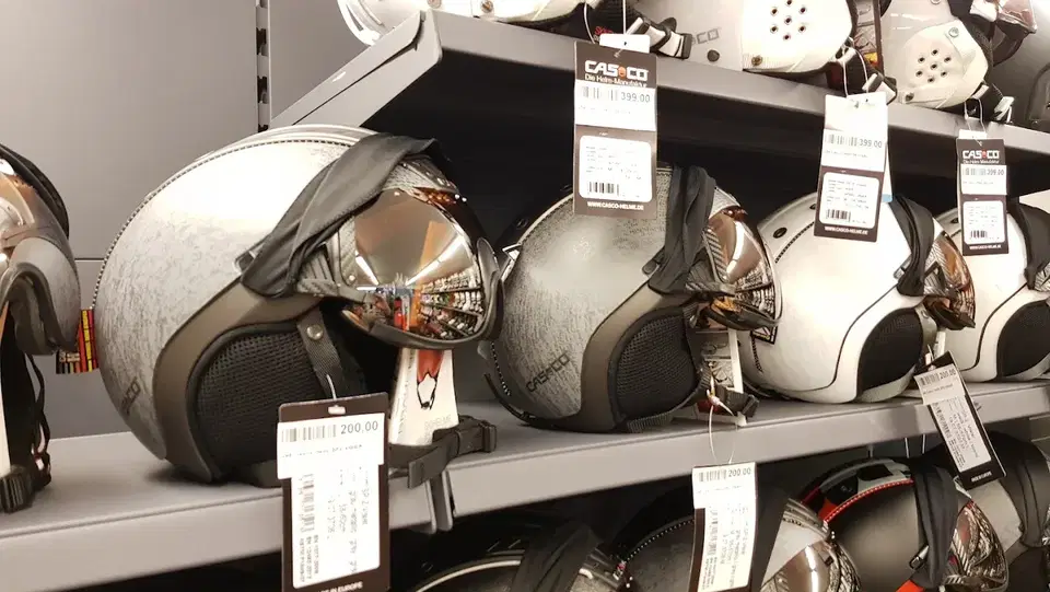 Mehrere silberne Casco-Integralhelme hängen an einem Verkaufsregal mit Preisschildern.