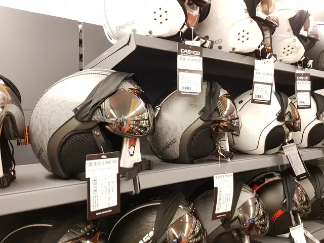 Mehrere silberne Casco-Integralhelme hängen an einem Verkaufsregal mit Preisschildern.