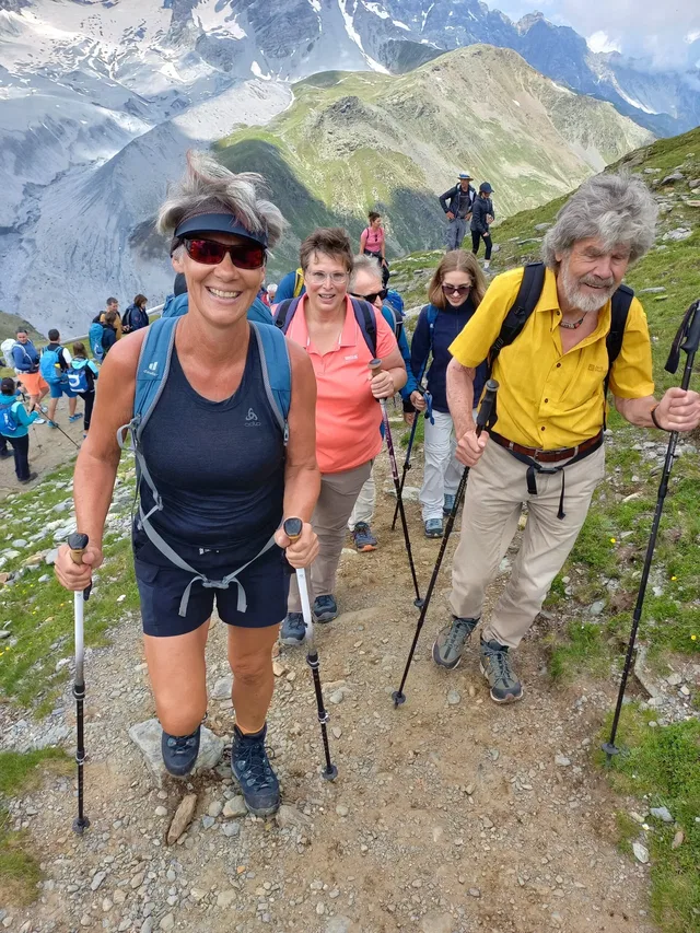 Wandergruppe auf einem Bergpfad vor alpiner Landschaft.