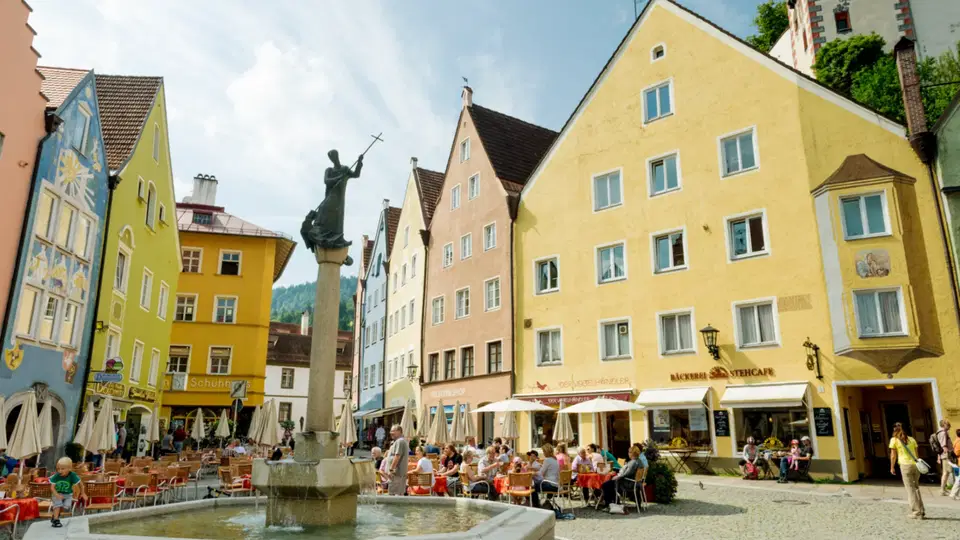 Historischer Stadtplatz mit Brunnen, bunten Häusern und Straßencafés