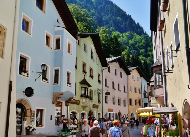 Historische Gasse mit Geschäften, Marktständen und bewaldetem Berghang