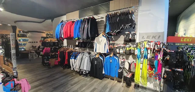 Innenansicht eines Sportgeschäfts mit Wand- und Bodenhängern für Kleidung und Ausrüstung.