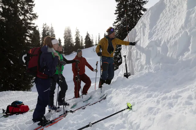 Gruppe von Skitouristen am Schneehang, Guide erklärt den sicheren Aufstieg an einer Schneewand.