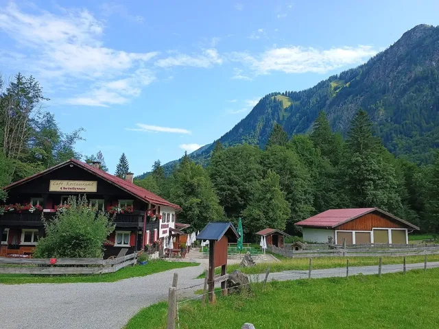 Bergdorf mit Holzhäusern, Wiesen und Wald vor Bergkulisse