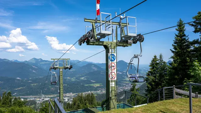 Einzelsessel des Kaiserlifts Kufstein im oberen Streckenabschnitt vor der Berglandschaft. Ortsmotiv.