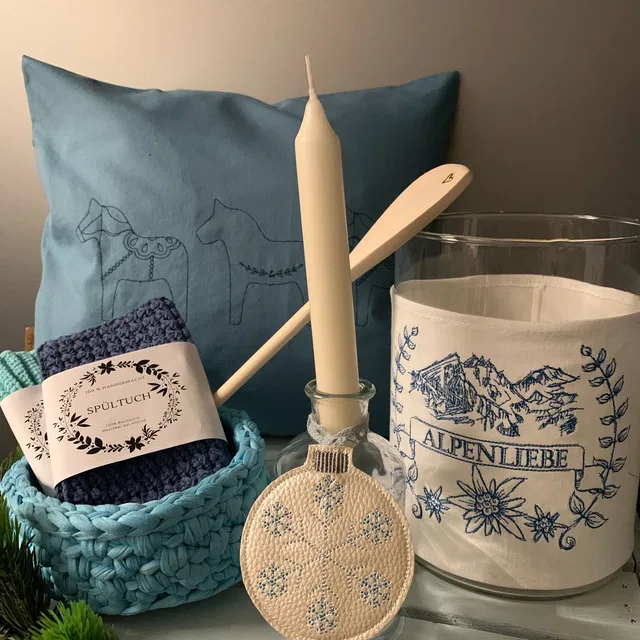 Blaues Kissen mit Pferdemotiv, Körbchen mit Spültuch und Leuchtenschirm mit Alpenliebe-Schriftzug.
